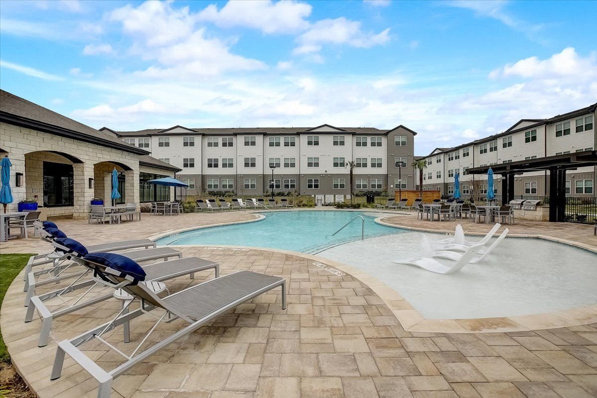 Resort-style pool courtyard with tanning ledge, in-water loungers, and ample deck seating.